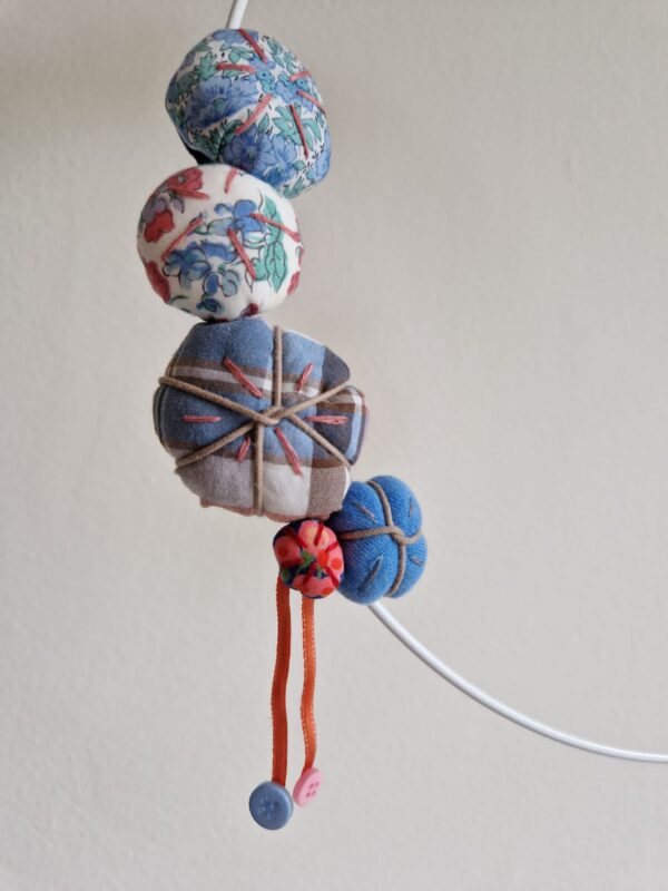 Detail of Wreath I. Kanzashi flowers of blue and pink tinges with hanging buttons.